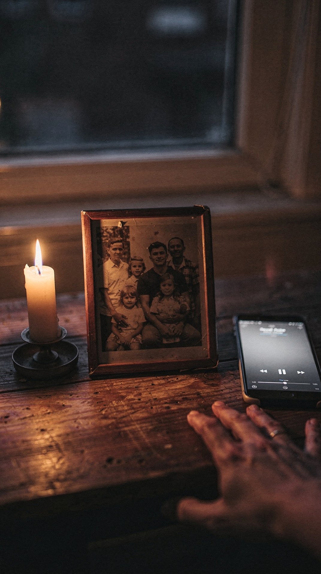Eine Hand hält ein altes Familienfoto neben einer Kerze